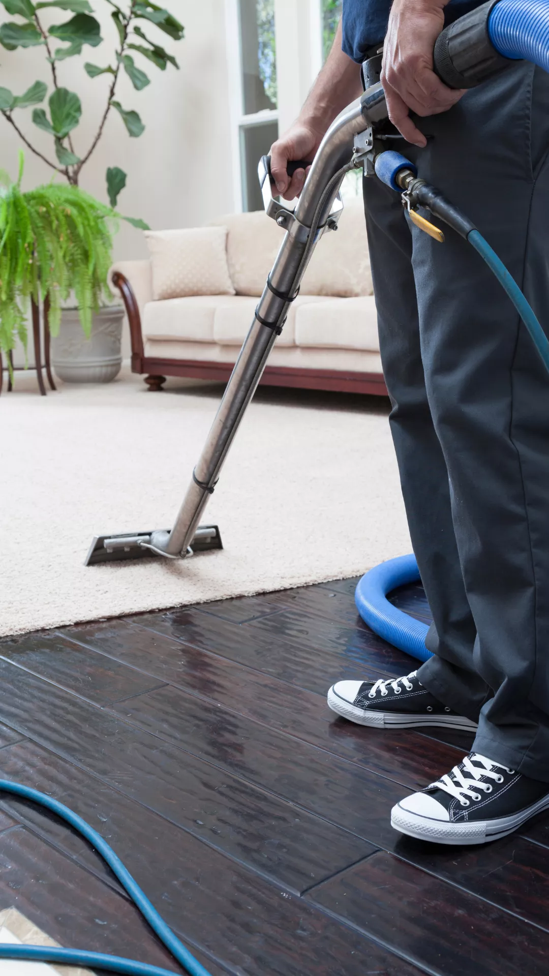 عامل نظافة يقوم بشفط الاتربة من السجاد باستخدام المكنسة الكهربائية