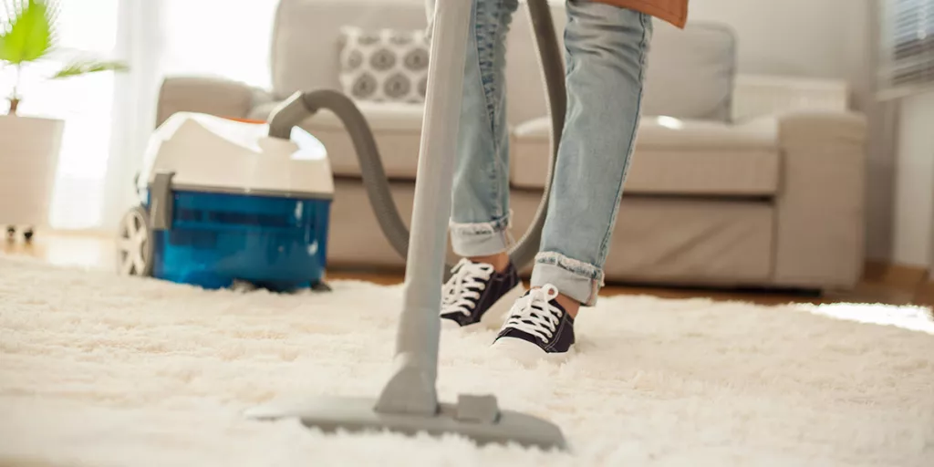 عاملة نظافة تقوم بتنظيف الاتربة من السجاد